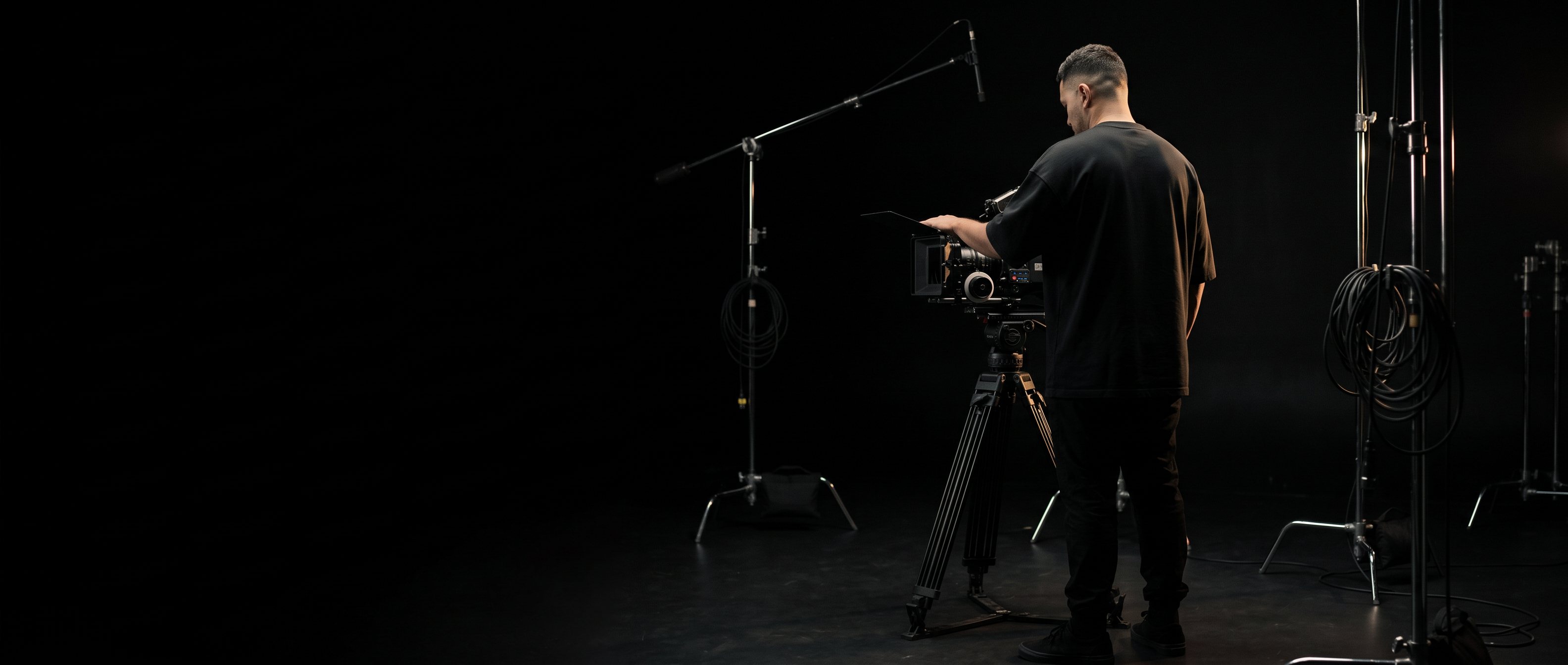 A man looking at a laptop in a dim room at night, back to camera.