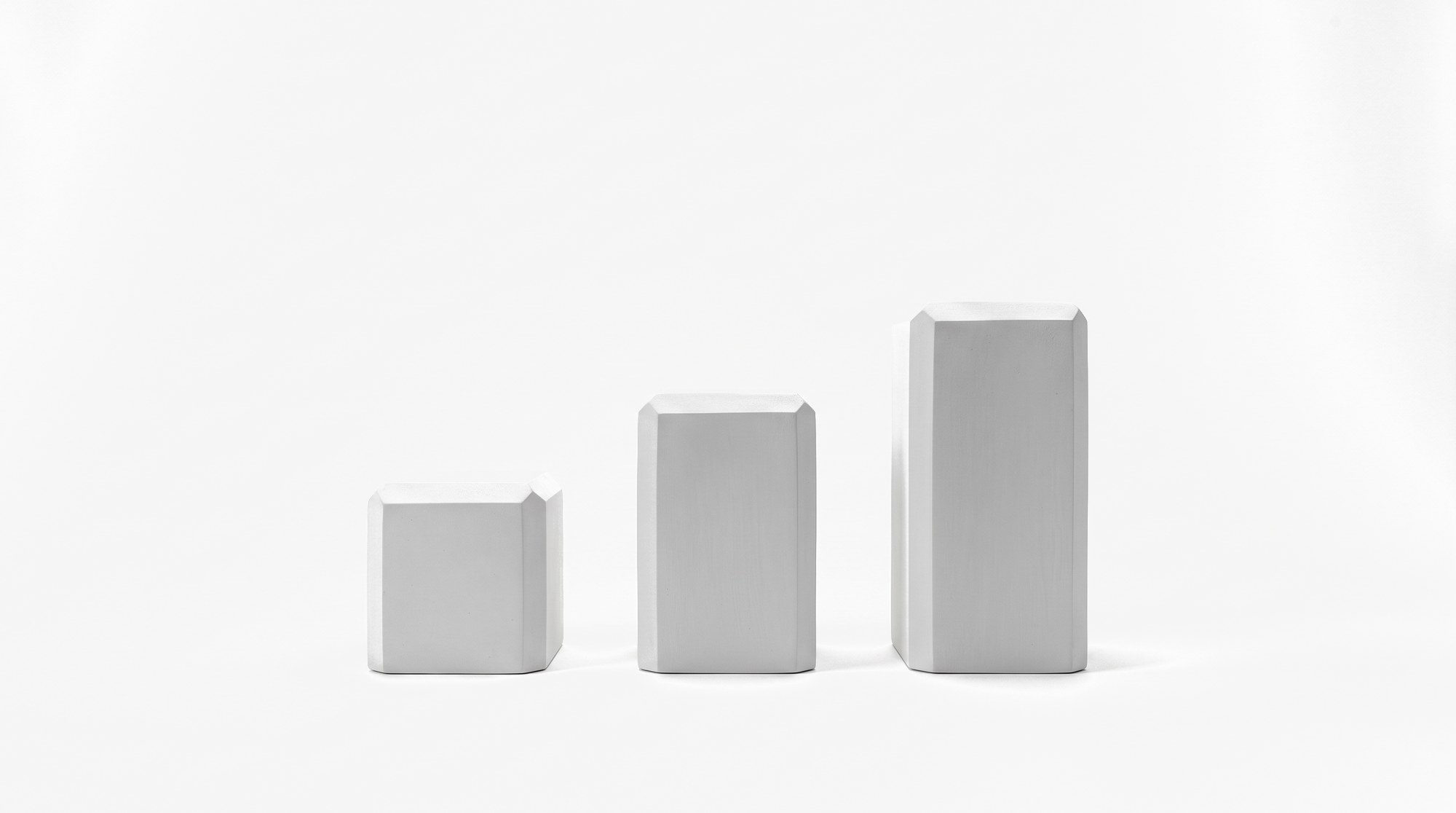 Three pale forms of ascending height standing in a row.