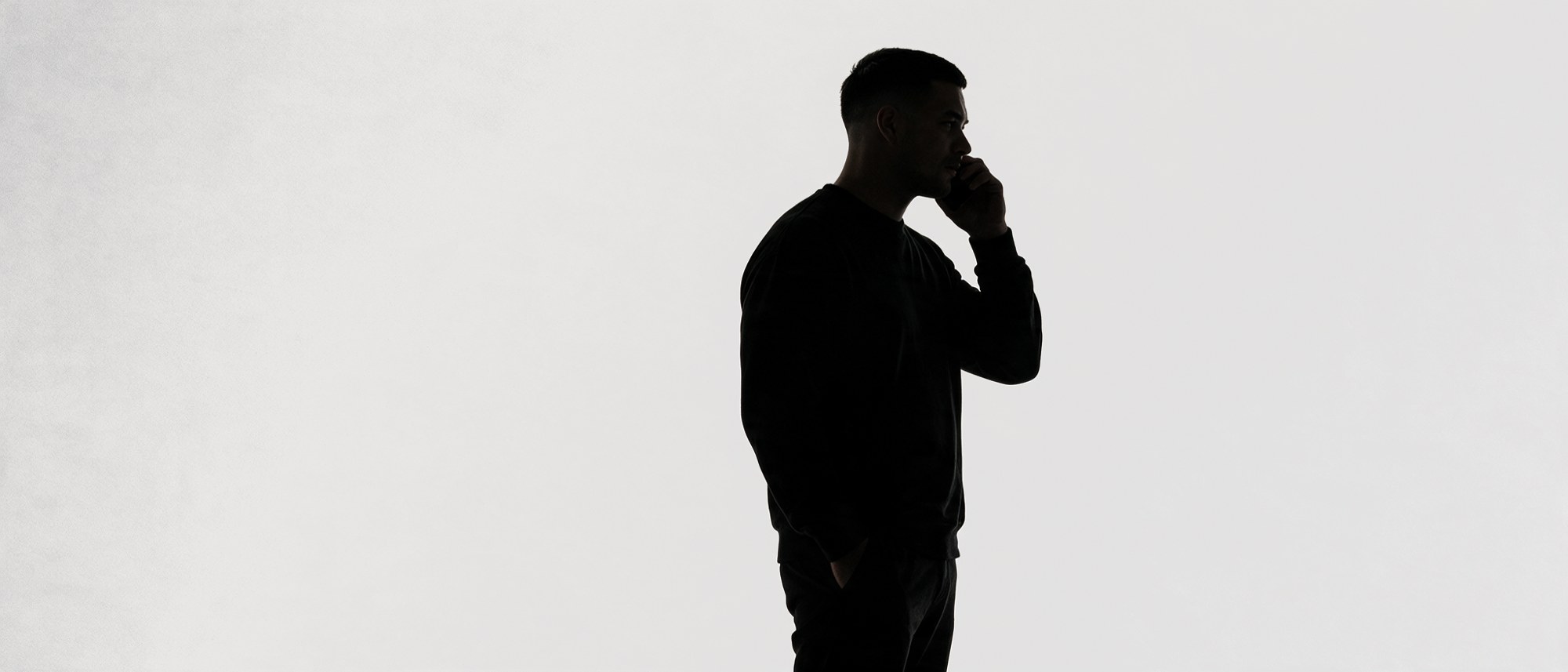 Silhouette standing with a phone to his ear.